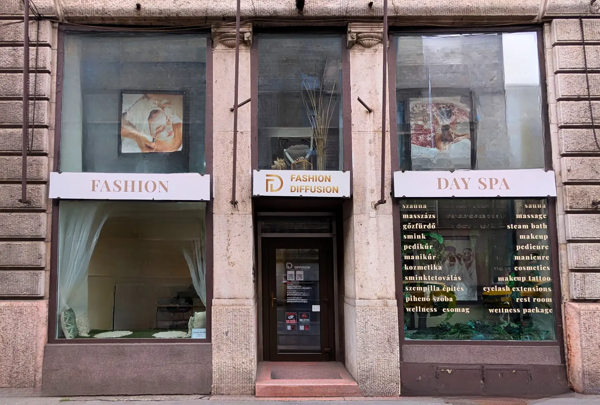 A szalon utcafronti portálja és bejárata: masszázs, kozmetika és day spa szolgáltatások listája a kirakaton.